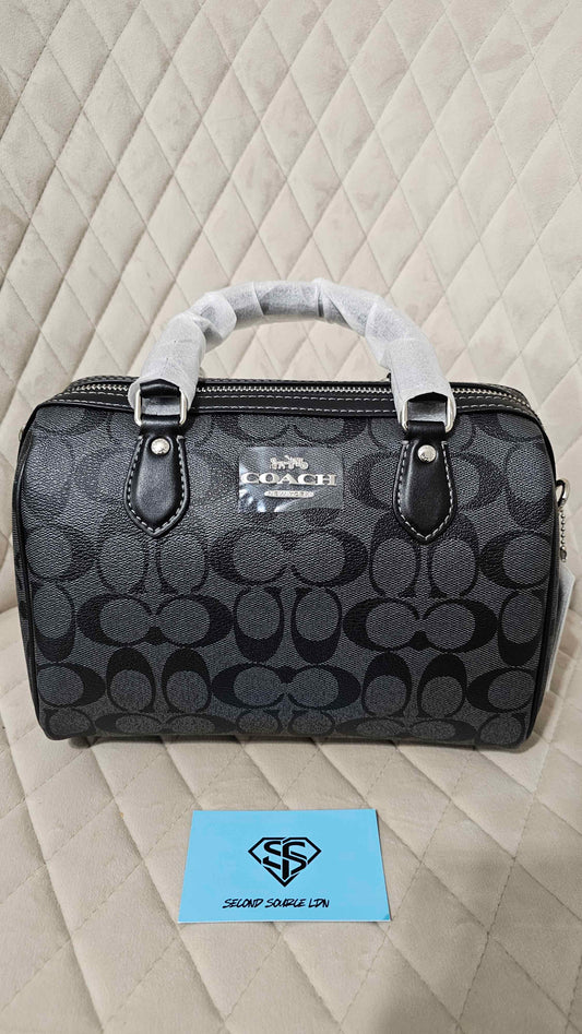 Coach handbag with a pattern on a quilted surface, featuring the Coach logo.